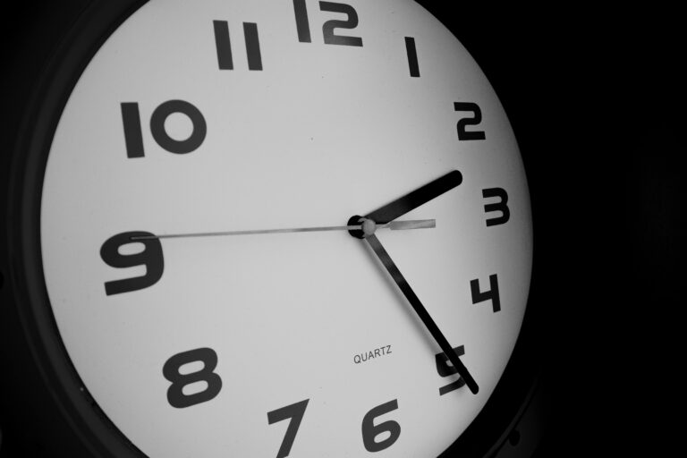 Black and white close-up of a wall clock showing nine o'clock.